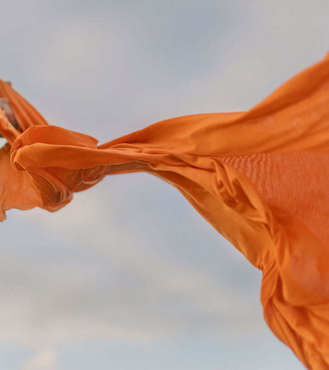 Close-up of orange circular economy textile fabric blowing in the wind — symbolising sustainable fashion innovation.