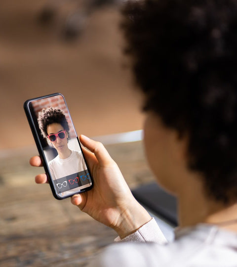 Person using AI-powered fashion retail app to try on glasses virtually, showing tech in shopping.