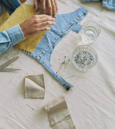 Hands mending colourful fabric — a visual of repair and reuse in fashion
