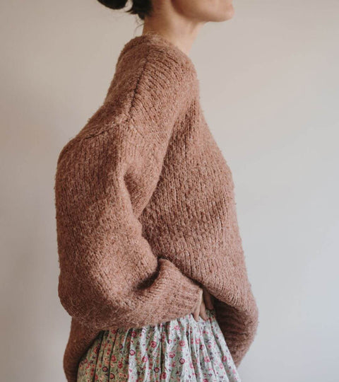 Why Your 100% Wool Sweater Might Contain Plastic, model wearing a textured pink sweater with oversized sleeves.