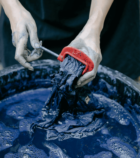 Person holding dyed fabric above a container.