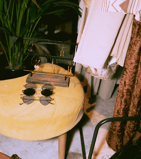 Colorful accessories and sunglasses on a yellow stool in a sustainable fashion resources display.