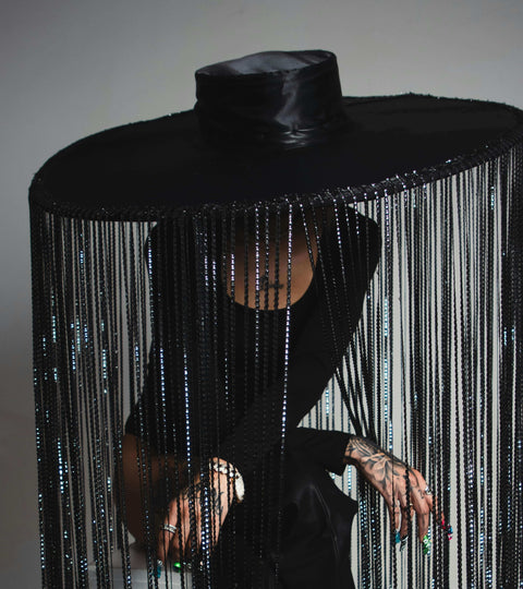 Fashion at the 2026 Grammys featuring a dramatic fringed black hat and stylish attire.