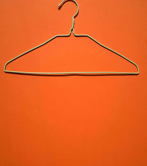 Colour Psychology in Fashion shown through a wire coat hanger on an orange background