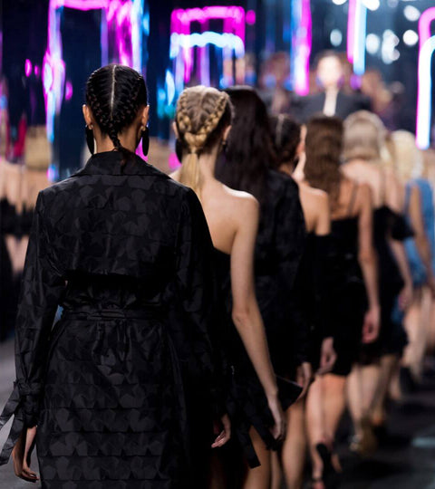 Models walking the runway at Copenhagen Fashion Week 2023 with vibrant lights in the background