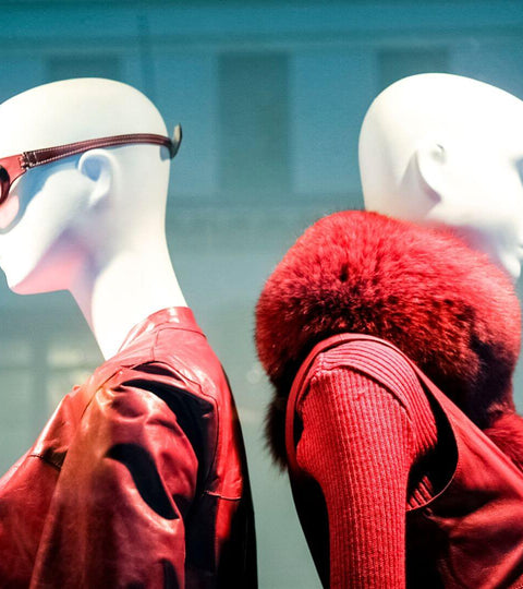 Two mannequins styled in red leather and fur outfits at London Fashion Week