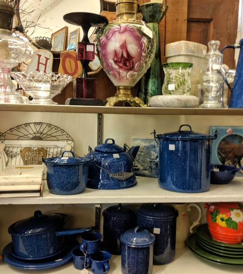 Thrift store shelves with vintage teapots, cookware, and decorative items on display