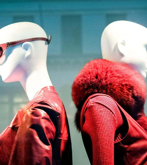 Two mannequins styled in red leather and fur outfits at London Fashion Week