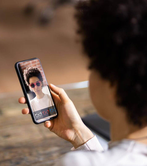 Person using AI-powered fashion retail app to try on glasses virtually, showing tech in shopping.