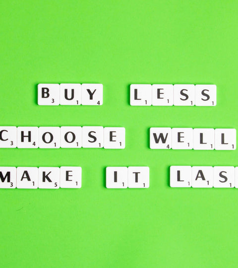 Green backdrop with scrabble letters spelling  buy less, choose well and make it last