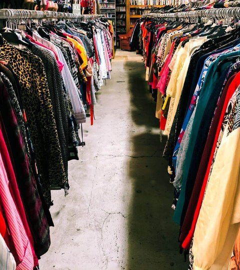 Second-hand fashion sustainability seen in a vibrant thrift store filled with colorful clothing racks.