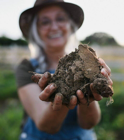 Woman holding soil to promote sustainable practices for regenerative fashion brands.