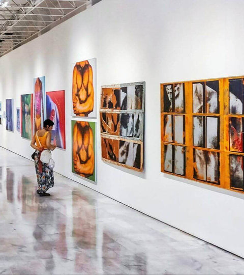 A large white-walled gallery space showcasing contemporary artworks, with bright lighting and clean architectural lines.