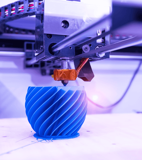 Close-up of a 3D printer creating a blue spiral object, representing innovation and sustainability in manufacturing.
