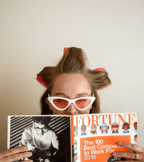 model with white cats eye sunglasses reading a magazine
