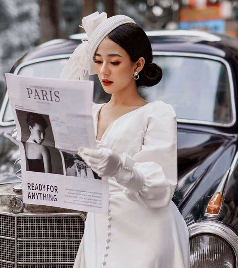 model wearing chic white outfit holding a french newspaper