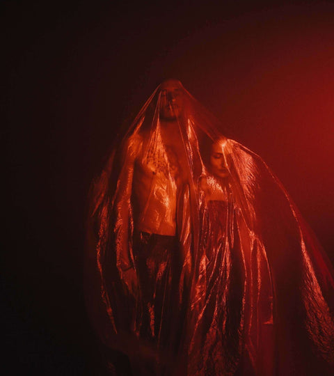 Models wearing recycled plastic textiles in an artistic, dramatic red-lit setting.
