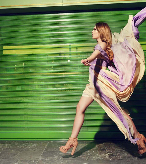 A model showcasing biodegradable fashion outfit with flowing fabric against a vibrant green backdrop.