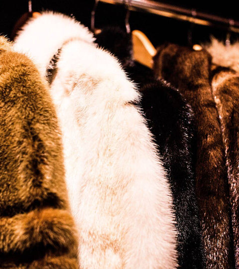 Various coats made from biodegradable faux fur displayed on a rack.