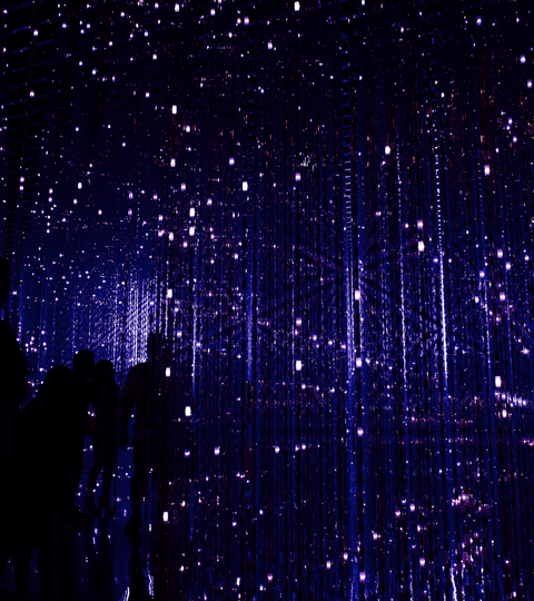 Digital influence on fashion trends showcased in a mesmerizing light installation with silhouettes of people.